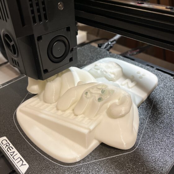 Fotografía de una impresora 3D, imprimiendo una réplica de una ilustración de Luis Braille en alto relieve.